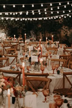 an outdoor wedding reception set up with white tablecloths, candles and centerpieces