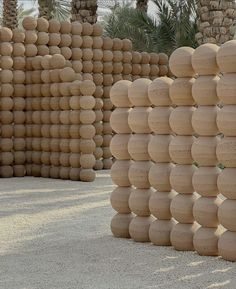 a large group of wooden balls stacked on top of each other in front of palm trees