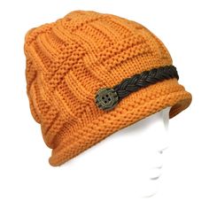 an orange knitted hat with a skull on the front and braiding around the brim