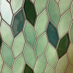 a close up view of a green and white tile wall with hexagonal shapes