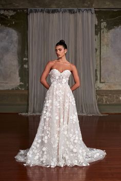 a woman in a wedding dress standing on a wooden floor with her hands on her hips