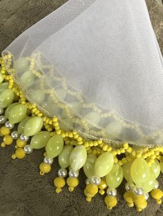 a yellow and white beaded necklace is on the ground next to a veil with pearls