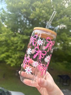 a person holding up a pink and white flowered tumbler with straw in it