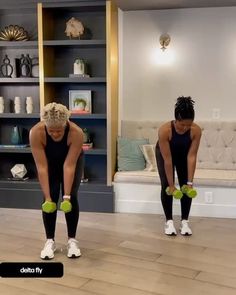 two women doing exercises with green dumbs in front of a bookshelf and couch