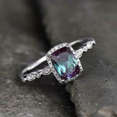 a ring with an amethorate and diamonds on it sitting on top of a rock