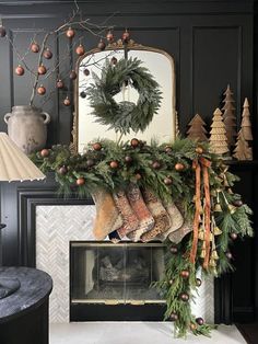 a fireplace decorated for christmas with stockings and pine cones