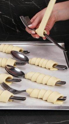 a person is holding a fork and knife over some uncooked ravioli on a pan