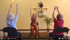 three older women sitting in chairs with their arms up and one woman holding her hands up