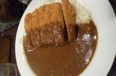 two pieces of bread on top of rice and gravy in a white plate