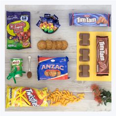 some snacks are laid out on a white wooden table with chocolate, candy bars and candies