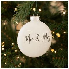 a white ornament hanging from a christmas tree with mr and mrs written on it