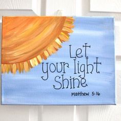 a painting with the words let your light shine written on it, hanging on a door