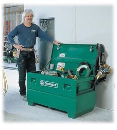 a man standing next to a green box filled with tools