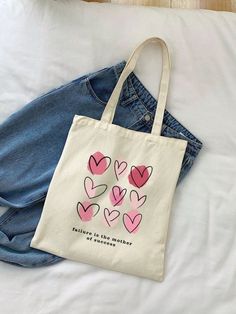 a tote bag sitting on top of a bed next to a pair of jeans