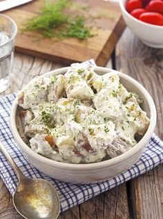 a white bowl filled with potato salad on top of a blue and white checkered napkin