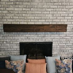 a living room with a brick fireplace and lots of pillows