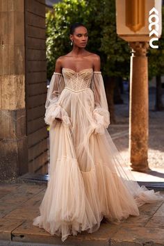 a model walks down the runway in an off - shoulder dress with long sleeves and sheer tulle