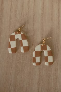 two pairs of wooden earrings with white and brown checkerboard design on them, one is