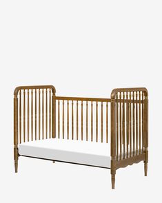 a wooden crib with white sheets on the bottom and side rails, in front of a gray background