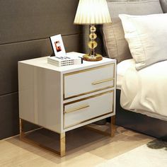 a night stand with two drawers and a lamp next to it on a wooden floor