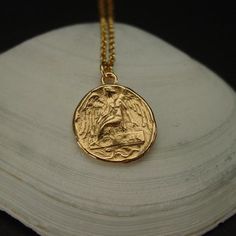 Handmade ancient greek coin reproduction of the winged Nike goddess necklace.In Greek Mythology, Nike was the goddess of speed, strength and victory. Also known as Winged Goddess, Nike is most often pictured as having wings. Ancient Greeks worshiped Nike because they believed she could make them immortal and was able to grant to humans strength and the speed needed to be victorious in any task they undertook.When Nike appeared alone, she always had wings and sported a palm branch in her right ha Mythological Style Round Jewelry Gift, Mythological Round Pendant Jewelry As Gift, Mythological Medallion Jewelry Gift, Mythological Round Pendant Necklace For Gifts, Spiritual Winged Jewelry For Gift, Gold Winged Necklace Perfect As A Gift, Goddess Of Victory Nike, Gold Engraved Goddess Style Necklaces, Handmade Gold Goddess Necklace