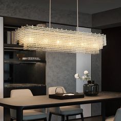 a modern chandelier hanging over a dining room table with chairs and vases