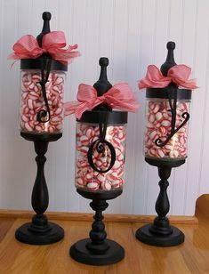 three black candle holders with candy in them