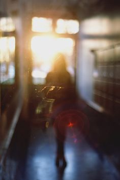 a blurry image of a person walking on a subway platform at sunset or sunrise