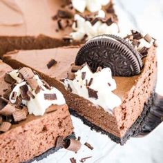 an oreo cookie and chocolate cheesecake on a glass cake plate with one slice taken out