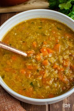 a bowl of soup with carrots, celery and parsley on the side