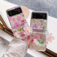 two phone cases with flowers on them sitting next to each other in front of a window