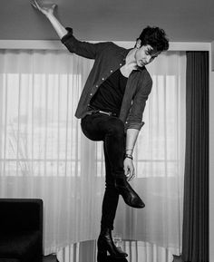 black and white photograph of a man jumping in the air with his foot on a table