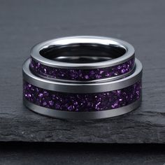 two rings with purple glitter in them on top of a black stone slabd surface