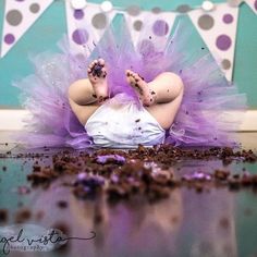 a baby in a purple tutu laying on the floor