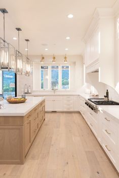 a large kitchen with white cabinets and wood flooring on the countertops, along with a bowl of fruit