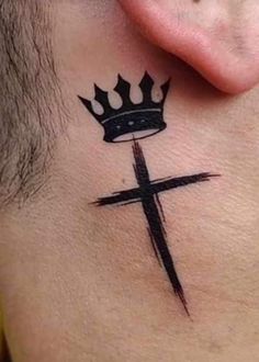 a cross with a crown on top of it and a tattoo behind the ear that says,