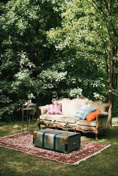 a couch, table and trunk in the grass