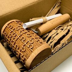 an open cardboard box with some wooden items in it's lid and two pens on top