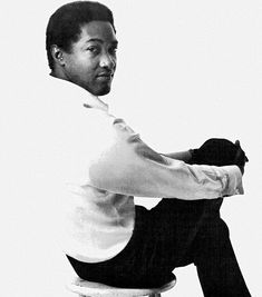 a black and white photo of a man sitting on a stool