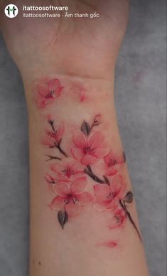 a wrist tattoo with pink flowers on it