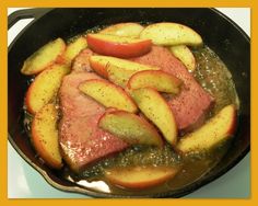 meat and apples cooking in a skillet on the stove with seasoning over them