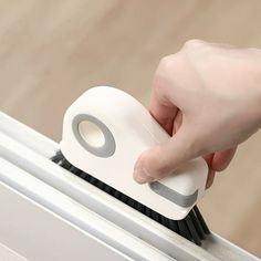 a person is using a brush to clean the window sill