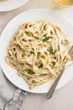 a white plate topped with pasta covered in sauce and garnished with parsley