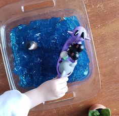 a baby's hand is holding a toothbrush in front of an ice tray