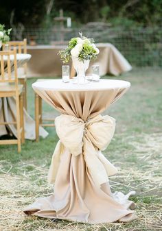 a table with a bow on it and flowers in vases sitting on top of it