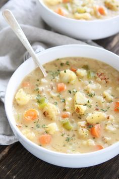 a white bowl filled with soup on top of a gray napkin and a spoon in it