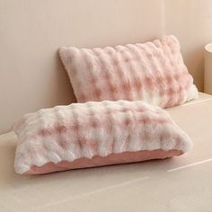 two pink pillows sitting on top of a bed