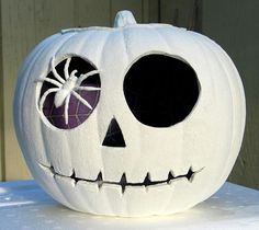 a white pumpkin with two eyes and a spider on it