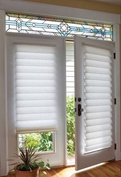 two white windows with blinds on them and a potted plant