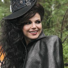 a woman with long hair wearing a black top hat and leather jacket in the woods